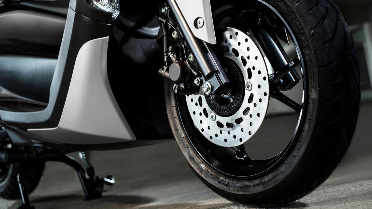 Detail image of Yamaha NMAX 155 scooter in white colourway, front wheel, brakes and suspension