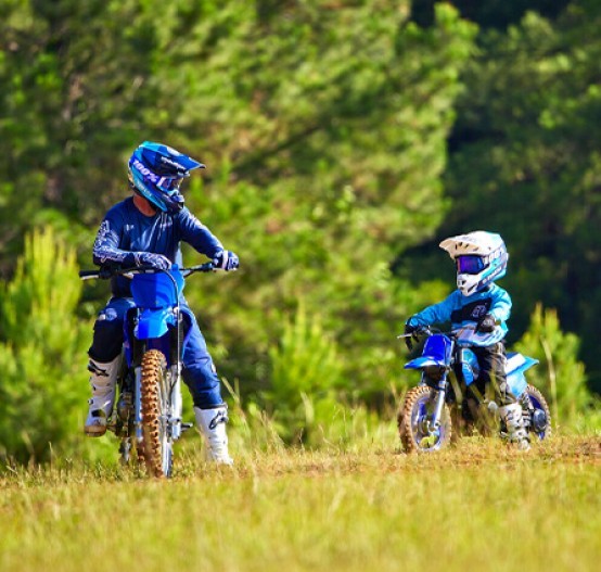 Adult and child riding on Yamaha off-road bikes including PW50 (PeeWee) in Blue colourway.