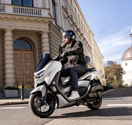 Action image of Yamaha NMAX 155 scooter in white colourway, turning on city street