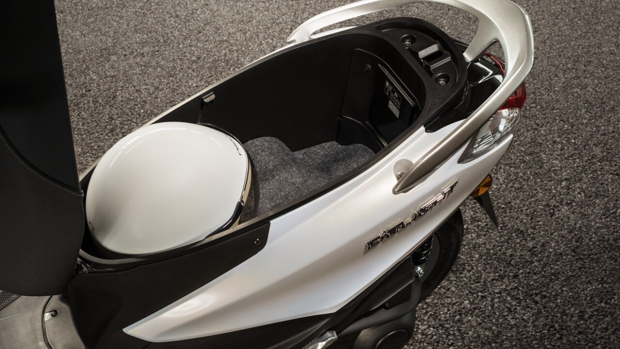 Studio image of Yamaha D'elight 125 scooter in pearl white colourway, underseat storage compartment with helmet