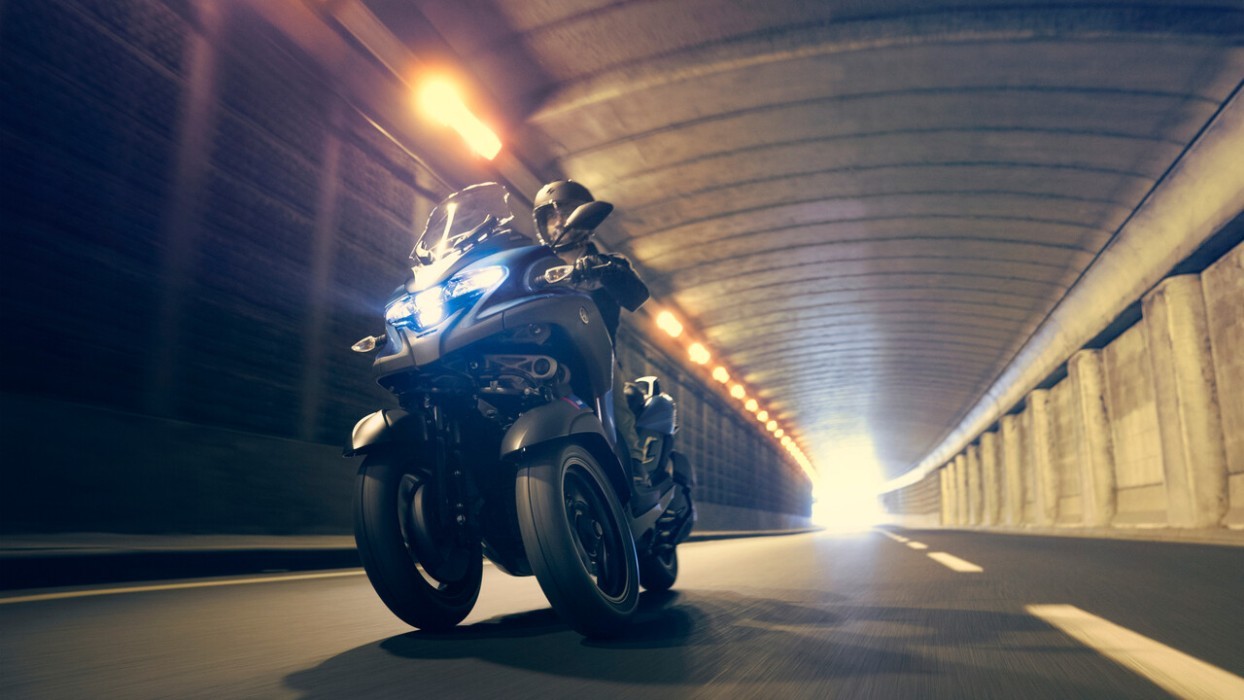 Action image of Yamaha Tricity 300 in blue colourway, riding through city tunnel