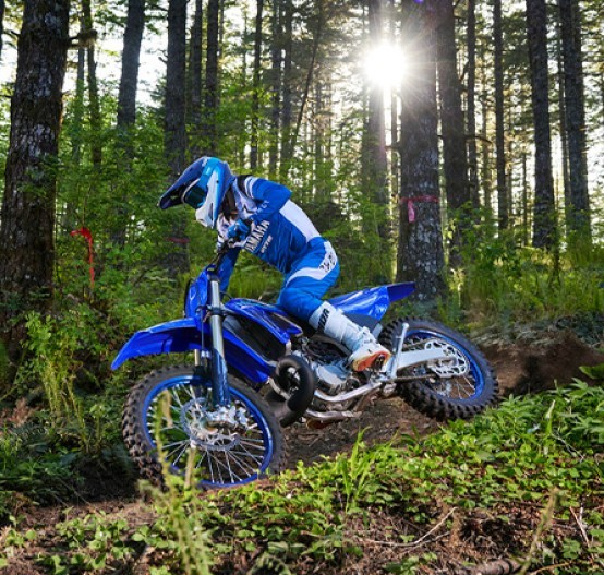 Action image of Yamaha YZ250X two stroke in blue colourway, riding through forest track