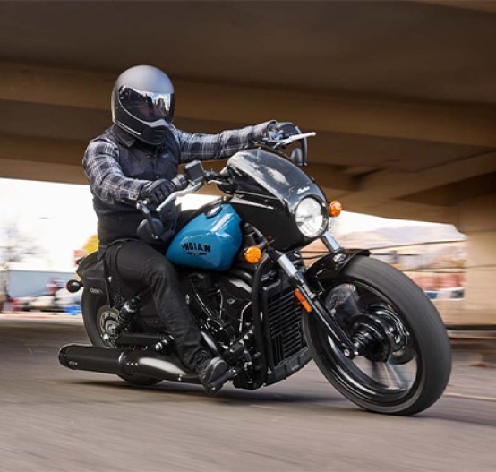Action image of Indian Sport Scout 2025 cruiser in Storm Blue Colour, tracking shot through turn riding under a bridge