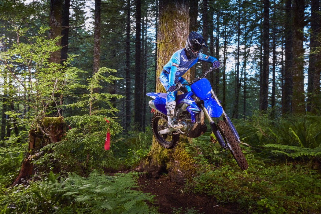 YZ450FX 2025 static image of enduro bike doing jump in forest