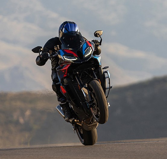 Action image of 2024 BMW M 1000 XR Competition in Black Storm Metallic/M Motorsport, motorcycle is shown head on while doing a wheelie/wheelstand