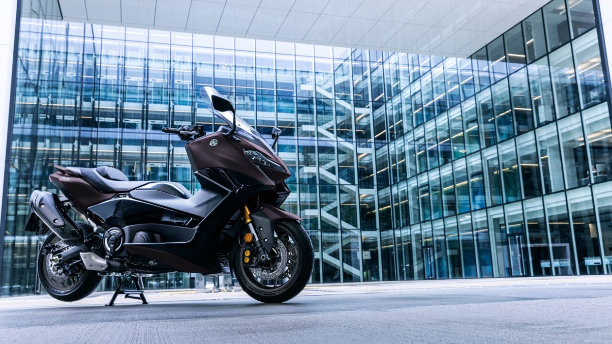 static image of Yamaha TMAX 560, parked in CBD square with glass office building background