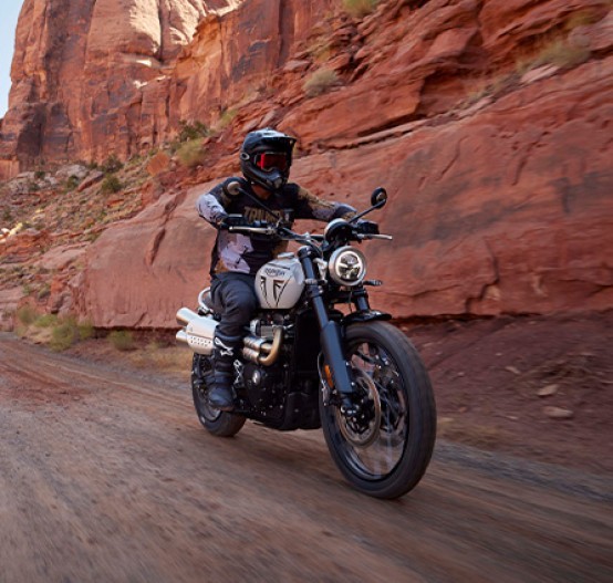 Action image of Triumph Scrambler 1200 X In Ash Grey, riding off road through mountain pass