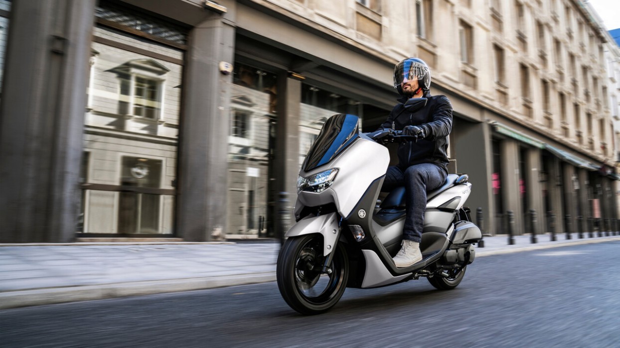 Action image of Yamaha NMAX 155 scooter in white colourway, front three quarter tracking shot