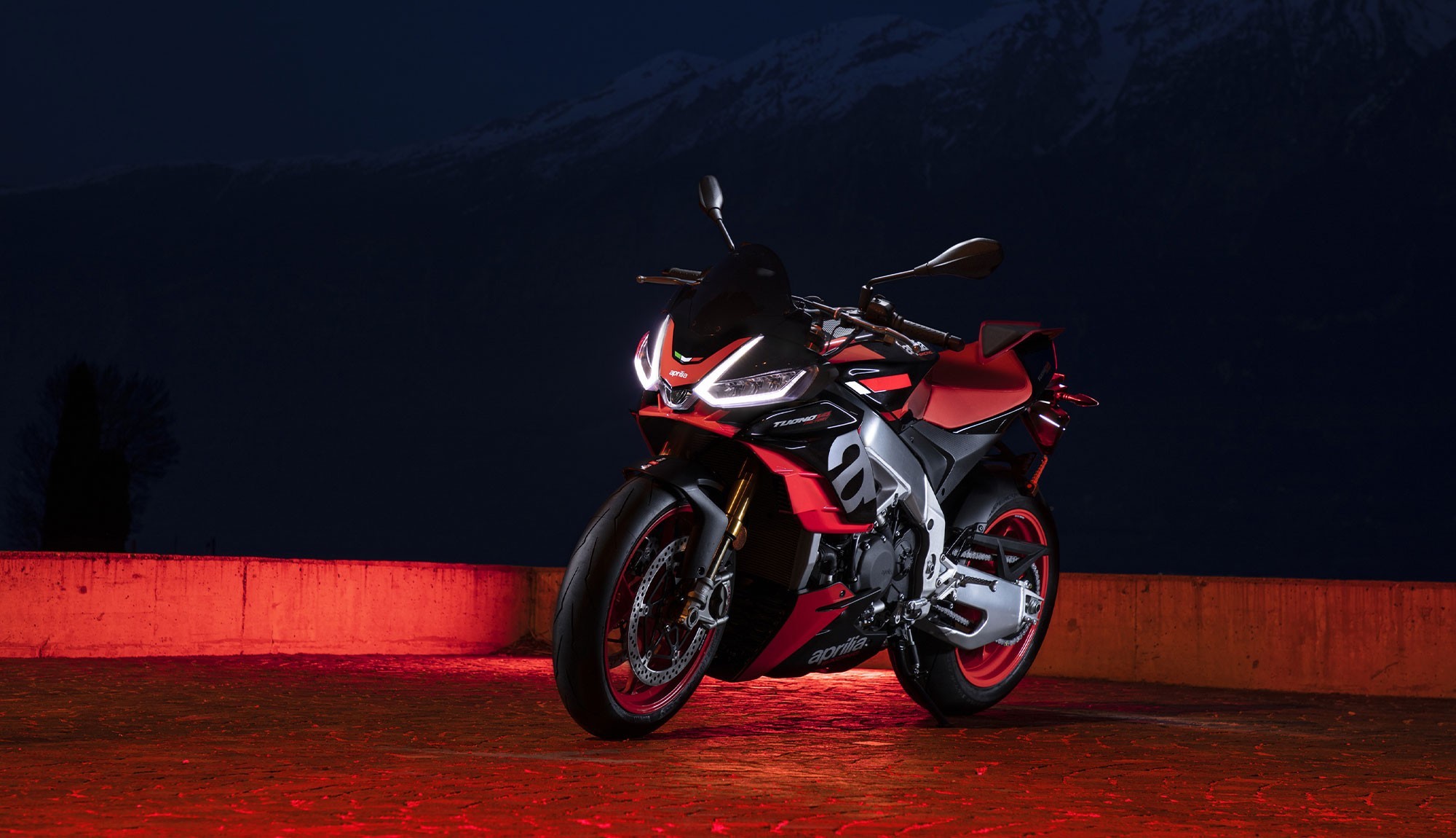 Front three quarter image of Aprilia Tuono Factory taken at night with red neon back light