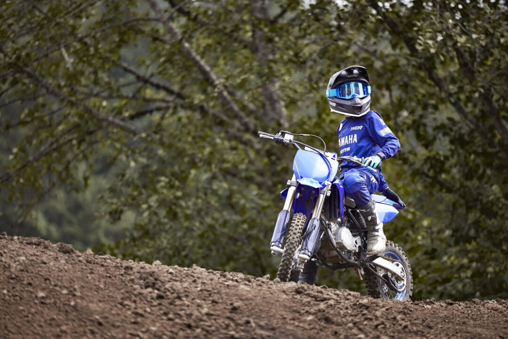 Static image of Yamaha YZ85 two stroke in Blue colourway. Motocross rider sitting on bike at outdoor racetrack