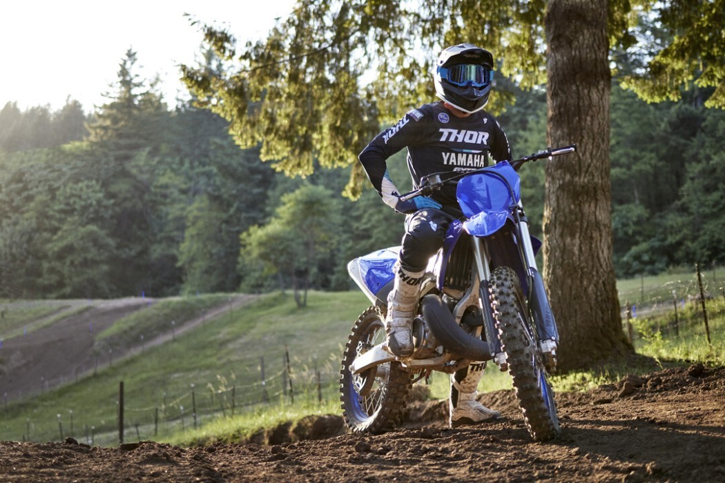 Static image of Yamaha YZ125 two stroke in Blue colourway, rider on bike facing camera with motocross track background