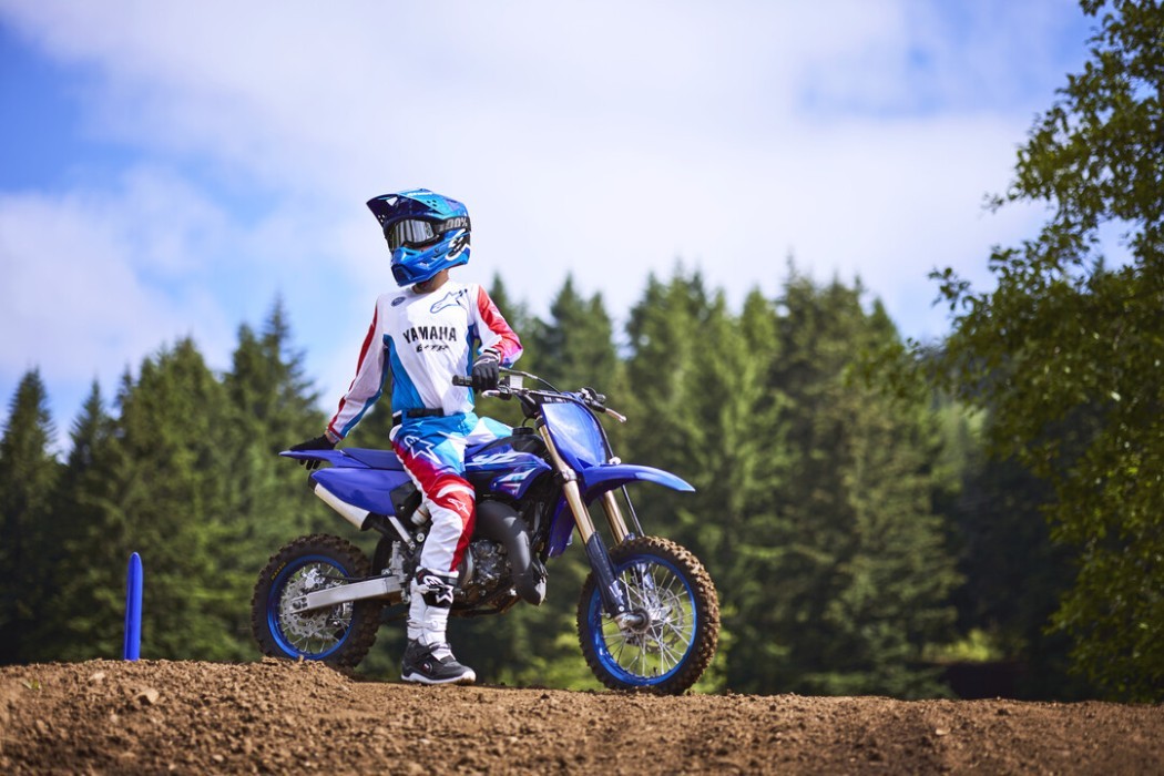 YZ65 2025 static image of motocross bike with rider standing on jump