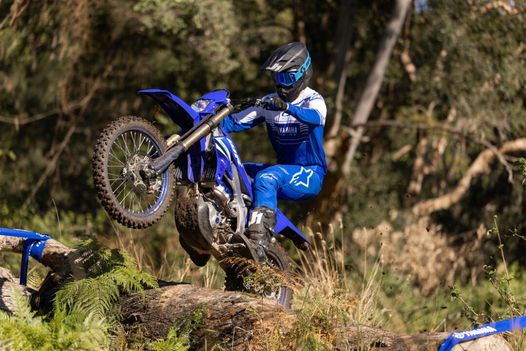 Yamaha WR450F 2025 in blue colourway, rider in action wheelie over log