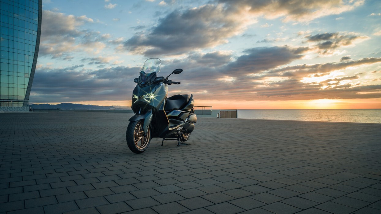 Static image of Yamaha XMAX 300 scooter in petrol green colourway, CBD square by the ocean